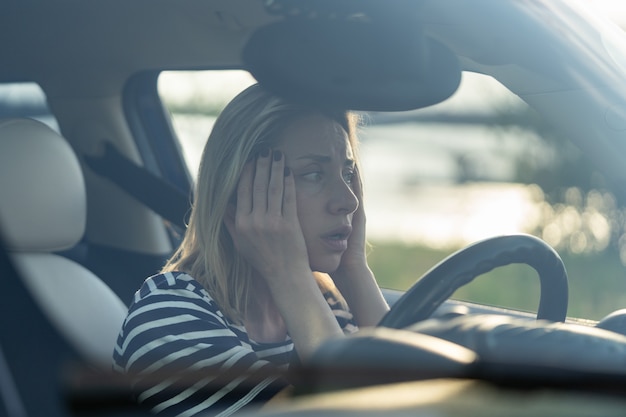 Verängstigte Frau sitzt am Fahrersitz im Auto und hat Angst, ein ängstliches weibliches Auto mittleren Alters zu fahren