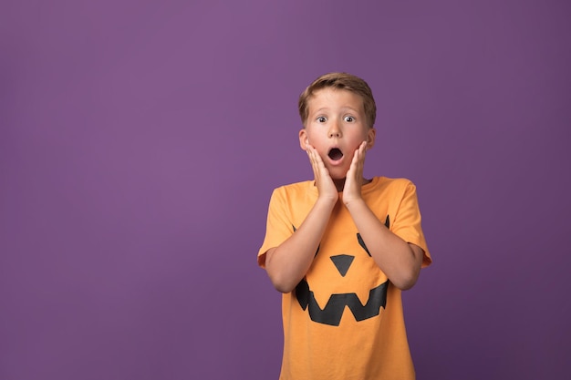 Foto verängstigter kleiner junge im halloween-outfit posiert auf lila hintergrund studioaufnahme