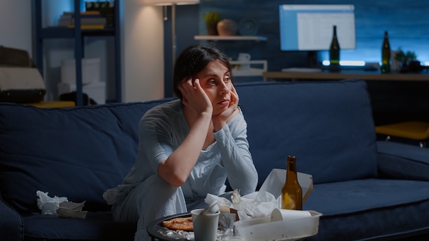 Verärgerte deprimierte enttäuschte Frau, die im Fernsehen verloren aussieht und an phychotischen Gedanken leidet, die an ...