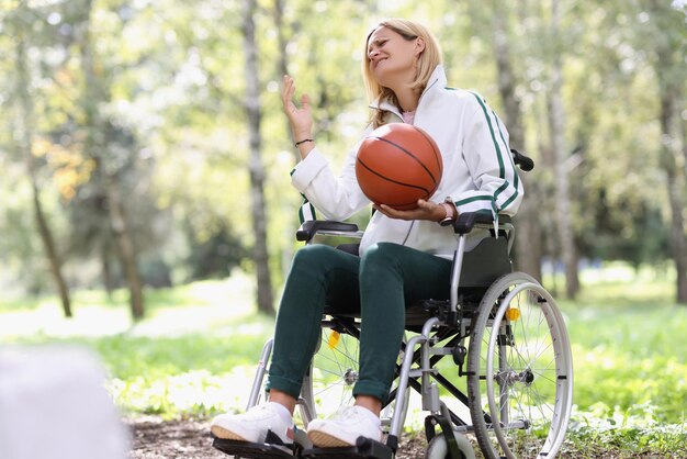 Verärgerte Frau, die im Rollstuhl sitzt und Basketballsport und Behindertenkonzept hält