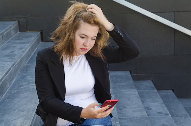 Verärgerte Frau mit einem Telefon in der Hand bekommt eine schlechte Nachricht, liest eine Nachricht, greift nach dem Kopf.