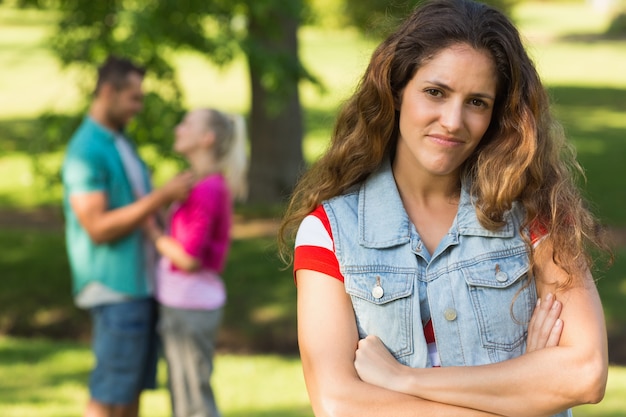 Verärgerte Frau mit Mann und Freundin im Hintergrund am Park