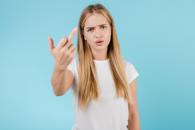 Verärgerte junge Frau, die den Mittelfinger lokalisiert über Blau zeigt