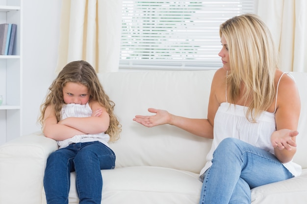 Verärgerte Mutter, die mit ihrer Tochter auf dem Sofa sitzt