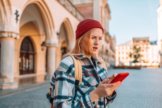 Verärgerte traurige, wütende Reisende Frau in stilvoller Kleidung hat eine schlechte SMS-Textnachricht in der alten Stadtstraße von Krakau Polen erhalten. Negative Emotionen