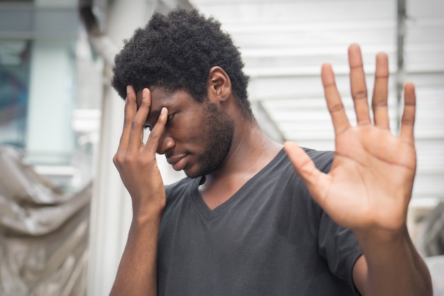 Verärgerter verärgerter afrikanischer Mann, der herauf Stopphandzeichen zeigt; Porträt eines frustrierten verärgerten afrikanischen Mannes oder schwarzen Mannes mit Stopp- oder Halt-Handgeste; Scheitern, Zurückweisen, Stoppkonzept; erwachsenes afrikanisches mann modell