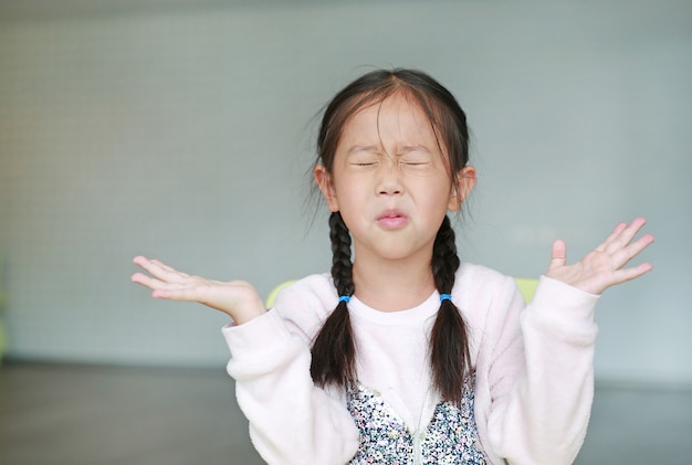 Verärgertes kleines asiatisches Kindermädchen im Klassenzimmer. Nicht zuhören. Zeichen und Gestenkonzept.