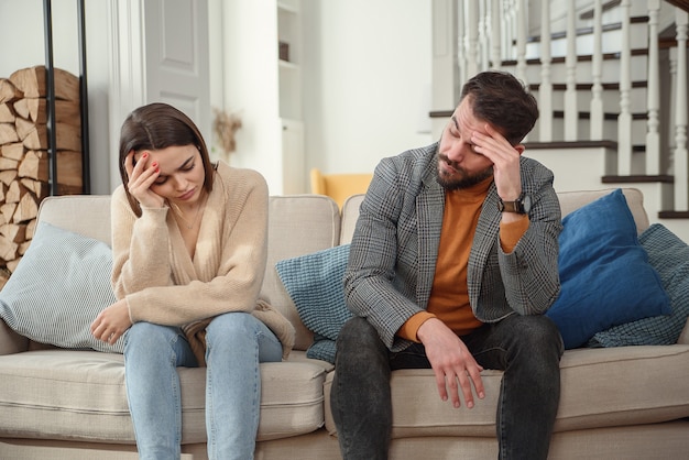 Verärgertes Paar zu Hause. Hübscher Mann und schöne junge Frau haben Streit. Zusammen auf dem Sofa sitzen. Familienprobleme.