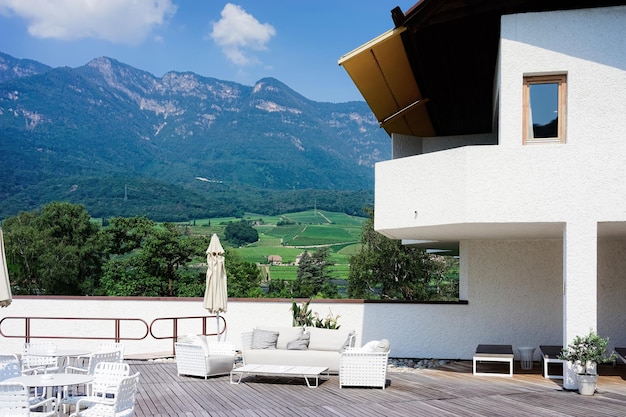 Veranda al aire libre en la calle con mesas y sillas de hotel de lujo moderno o arquitectura y paisaje de construcción de villas. Lago Caldaro en Tirol del Sur en Italia. Estilo de vida. balneario italiano. Diseño. Técnica mixta.