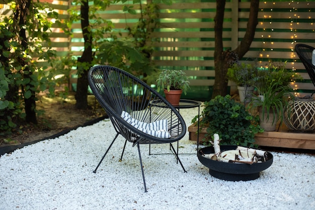 Veranda des Hauses mit schwarzem Acapulco-Sesseltisch und schwarzer Metallkaminschale im Garten