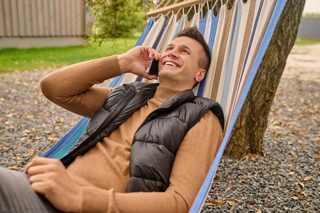 Veraneante alegre que tiene una conversación telefónica al aire libre