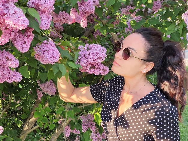 Verano una chica con gafas de sol con una bebida en sus manos arbusto lila