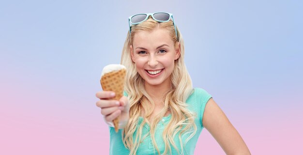 verano, comida chatarra y concepto de personas - mujer joven o adolescente con gafas de sol comiendo helado sobre cuarzo rosa y fondo degradado de serenidad