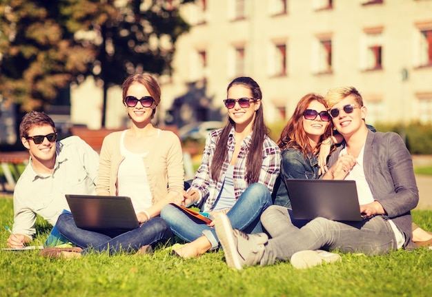 verano, internet, concepto de educación - grupo de estudiantes o adolescentes con laptop, cuadernos, archivos y carpetas