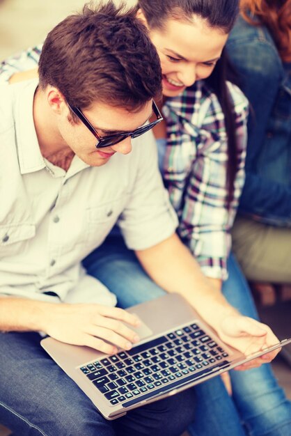 verano, internet, educación, campus y concepto adolescente - estudiantes o adolescentes con computadora portátil colgando