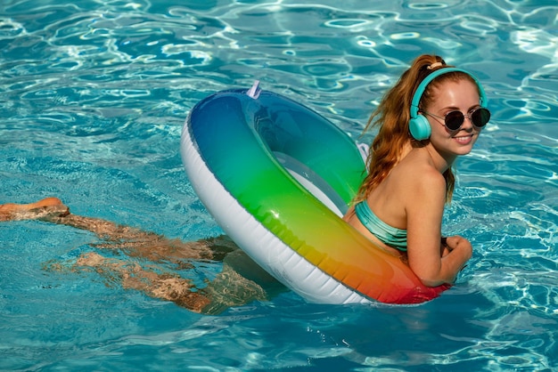 Verano joven disfrutando de mujer bronceada en traje de baño en círculo inflable en la piscina