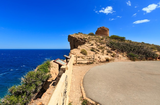Verano paisaje de la costa del mar Mediterráneo y ruinas de la torre Punta del Cavall (o Seguro) (del siglo XVI) cerca de la ciudad de Benidorm (Costa Blanca, Alicante, España).