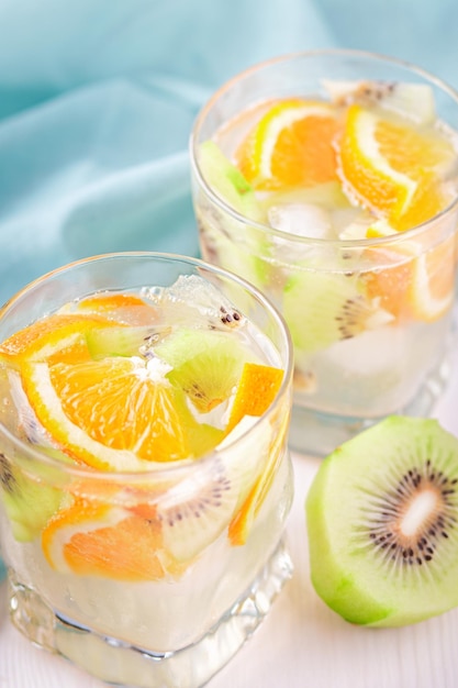 Verano refrescantes cócteles sin alcohol con naranja y kiwi closeup naturaleza muerta. Mocktail de verano con cítricos y agua con gas, concepto de estilo de vida saludable