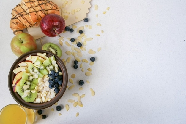 Verano saludable desayuno o merienda. Avena con bayas y frutas, jugo y krassan sobre una mesa plana blanca