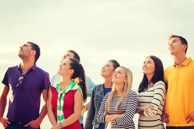 verano, vacaciones, vacaciones, concepto de gente feliz - grupo de amigos mirando hacia la playa