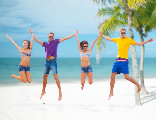 verano, vacaciones, vacaciones, concepto de gente feliz - grupo de amigos o parejas saltando en la playa