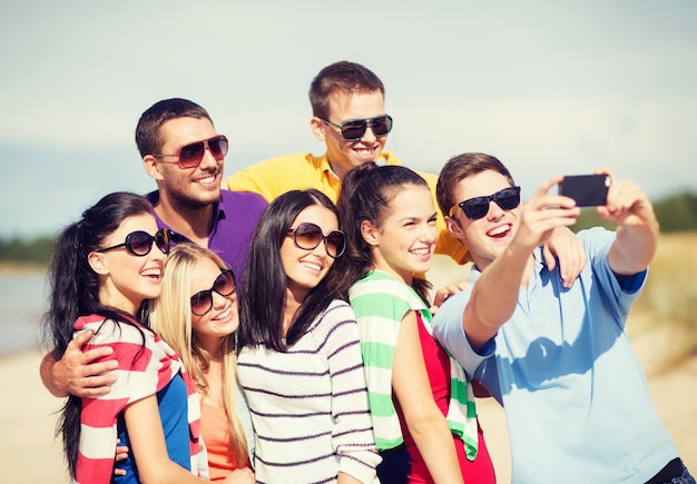 verano, vacaciones, vacaciones, concepto de gente feliz - grupo de amigos tomando fotos con smartphone