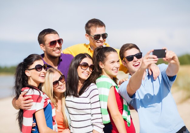 verão, feriados, férias, conceito de pessoas felizes - grupo de amigos tirando fotos com smartphone