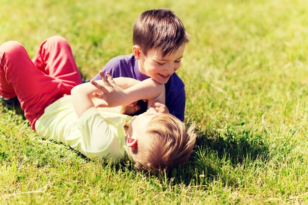 verão, infância, lazer e conceito de pessoas - meninos felizes ao ar livre lutando por diversão em campo verde