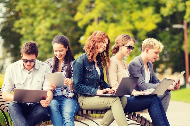 verão, internet, educação, campus e conceito adolescente - grupo de estudantes ou adolescentes com computadores laptop e tablet saindo