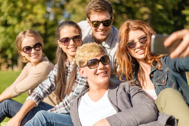 verão, internet, redes sociais, tecnologia e conceito adolescente - grupo de adolescentes tirando foto com a câmera do smartphone do lado de fora