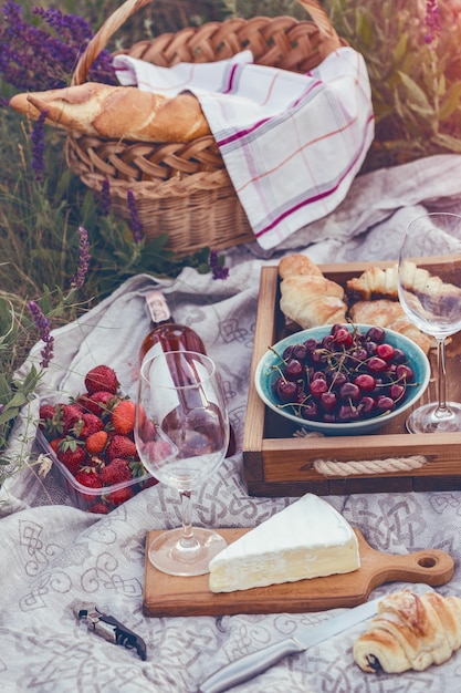 Verão - piquenique no prado. Queijo brie, baguete, morango, cereja, vinho, croissants e cesta