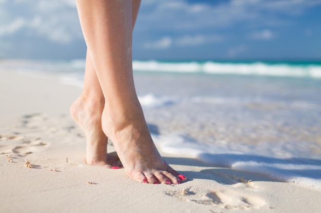 verão, praia, lazer e conceito de parte do corpo - closeup de pernas de mulher na beira-mar