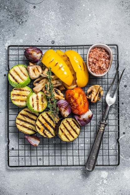 Foto verão sazonal legumes grelhados em uma grelha pimentão abobrinha berinjela cebola e tomate fundo cinza vista superior