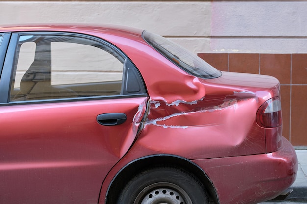 Verbeultes Auto mit beschädigter Karosserie auf der Straßenseite der Stadt geparkt. Verkehrssicherheits- und Kfz-Versicherungskonzept