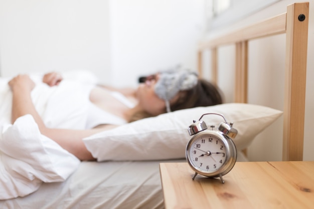 Foto verbinden sie das schlafen auf bett mit wecker über hölzernem schreibtisch