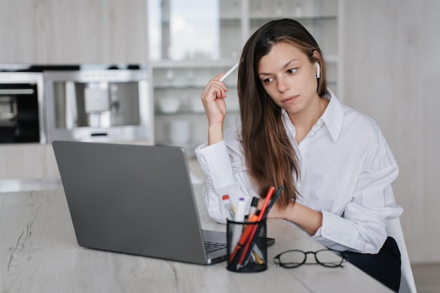 Verblüfft junge erwachsene Frau weißes Hemd Arbeit zu Hause mit Laptop Denken über neue Projekt schaut auf Bildschirm versucht, Problem zu lösen Overloaded Student Girl Remote Learning Business und Bildung