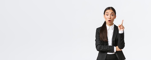 Verblüffte, intelligente asiatische unternehmerin, bauleiterin, hat einen großartigen plan, den finger nach oben zu heben, um eine lösung vorzuschlagen, die gedanken und ideen mit der gruppe, die auf weißem hintergrund steht, teilt