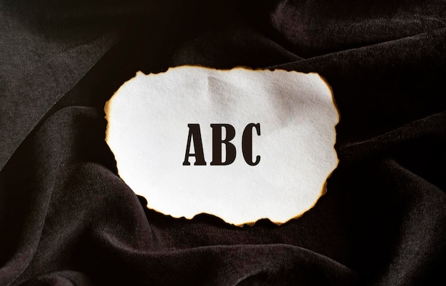 Verbranntes Papier auf schwarzem Hintergrund mit Text ABC