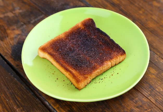 Verbranntes Toastbrot auf hellgrüner Platte auf Holztischhintergrund