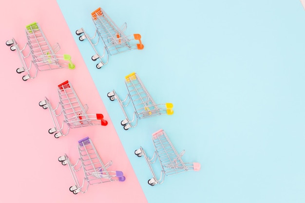 Verbraucherkonzept Minimalismus Mini-Einkaufswagen zum Einkaufen auf farbigem Hintergrund Draufsicht
