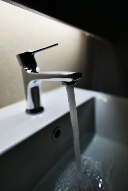 Verchromter Wasserhahn mit fließendem Wasser im Badezimmer