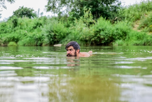 Verdadeira alegria. férias de verão. nadador maduro. hipster brutal com barba molhada. refrescante na água do rio. besta da água. monstro peludo. homem selvagem. hora de relaxar. homem barbudo nadando no lago.