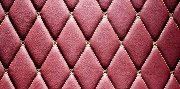 Verdadero lujoso de un elegante patrón geométrico vintage rojo carmesí asiento de cuero sofá cojines muebles tapizados en estilo retro con patrón de hilo cuero acolchado fondoCerca