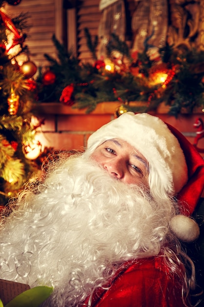 Verdadero Santa Claus. Papá Noel sentado en la sala de estar cerca del árbol de Navidad