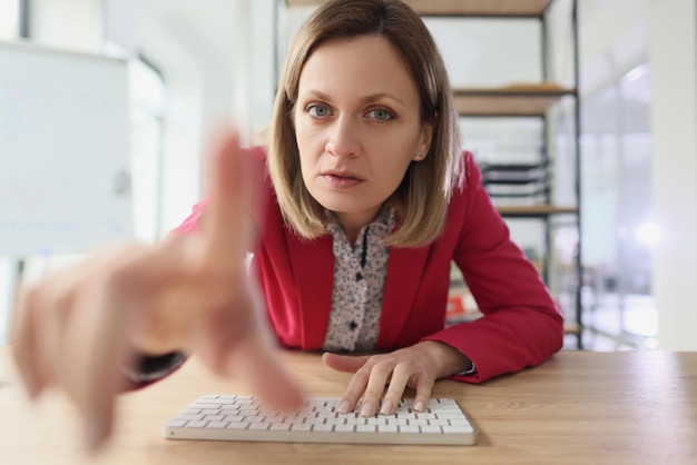 Verdächtige Frau zeigt mit dem Finger, um das Tippen auf der Tastatur zu überwachen