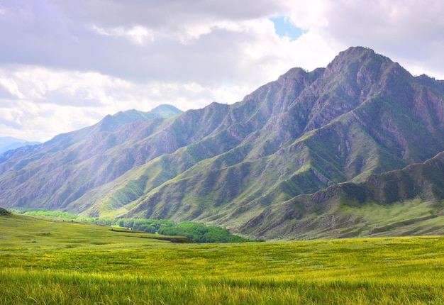 Verdes montañas rocosas en verano bajo un nublado cielo azul Siberia Rusia