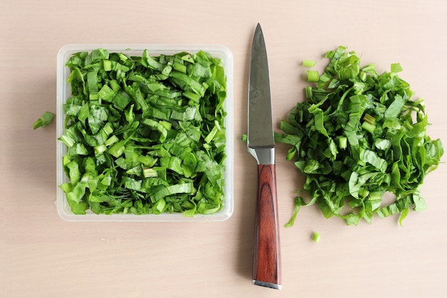 Verdes en rodajas y cuchillo en la mesa, vitaminas para vegetarianos, en plano