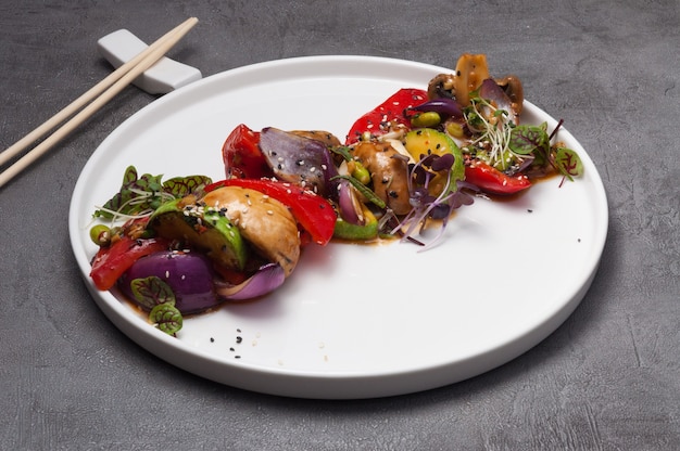 Verduras al horno y champiñones en una placa blanca.