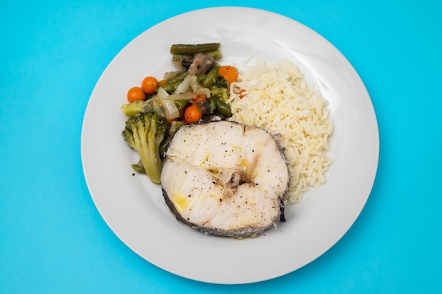 Verduras al horno con pescado hervido en plato blanco