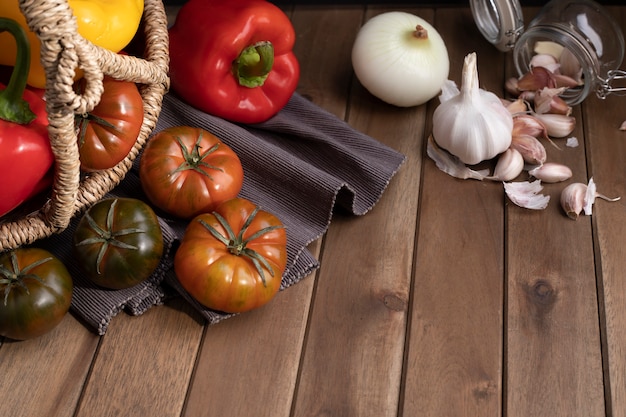 Foto verduras de alimentos orgánicos en cesta de mimbre en la mesa de madera rústica. vista cenital.